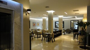 A spacious lobby with a marble floor, multiple tables and chairs, and a reception area with a counter. - Hotel Napoleon (Buenos Aires)