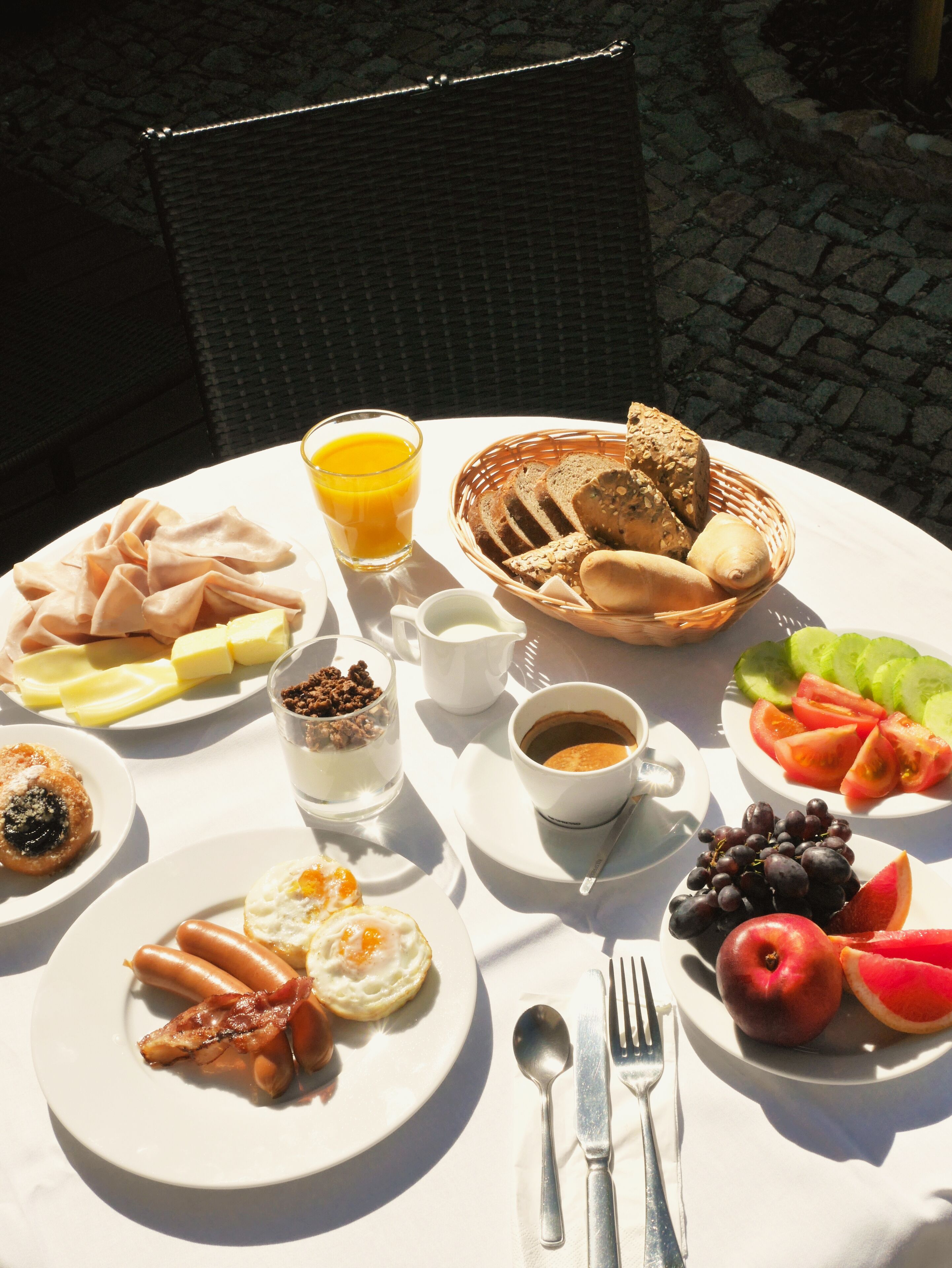 Ett frukostbord med olika rätter, inklusive ägg, bacon, rostat bröd och frukt.