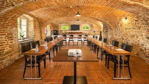Un salón de conferencias amplio con techo de ladrillo, mesas y sillas de madera.