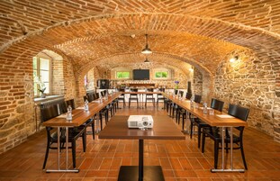 Un salón de conferencias amplio con techo de ladrillo, mesas y sillas de madera.