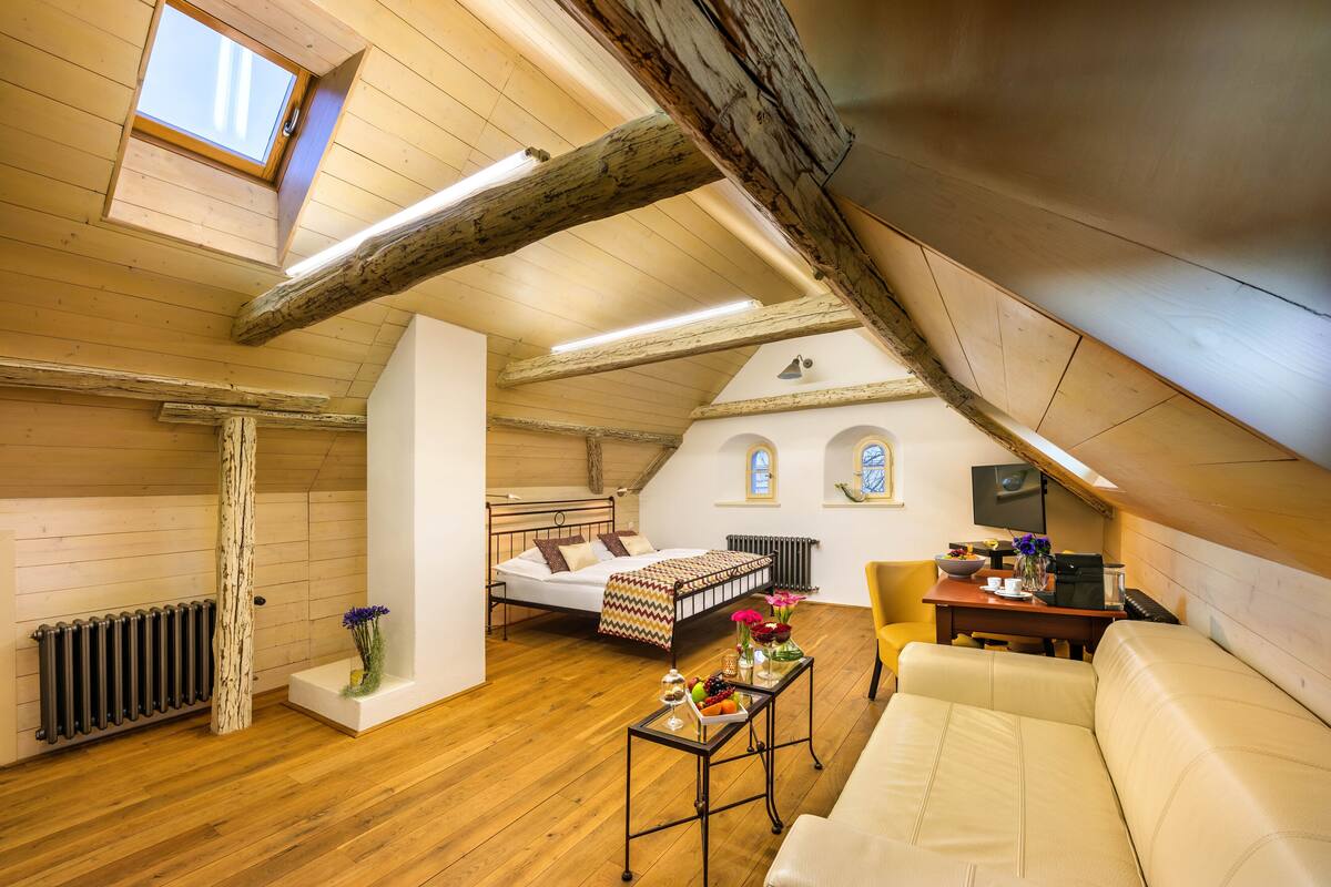 Un dormitorio acogedor en el ático con cama, sofá, mesa de comedor y pequeña cocina.