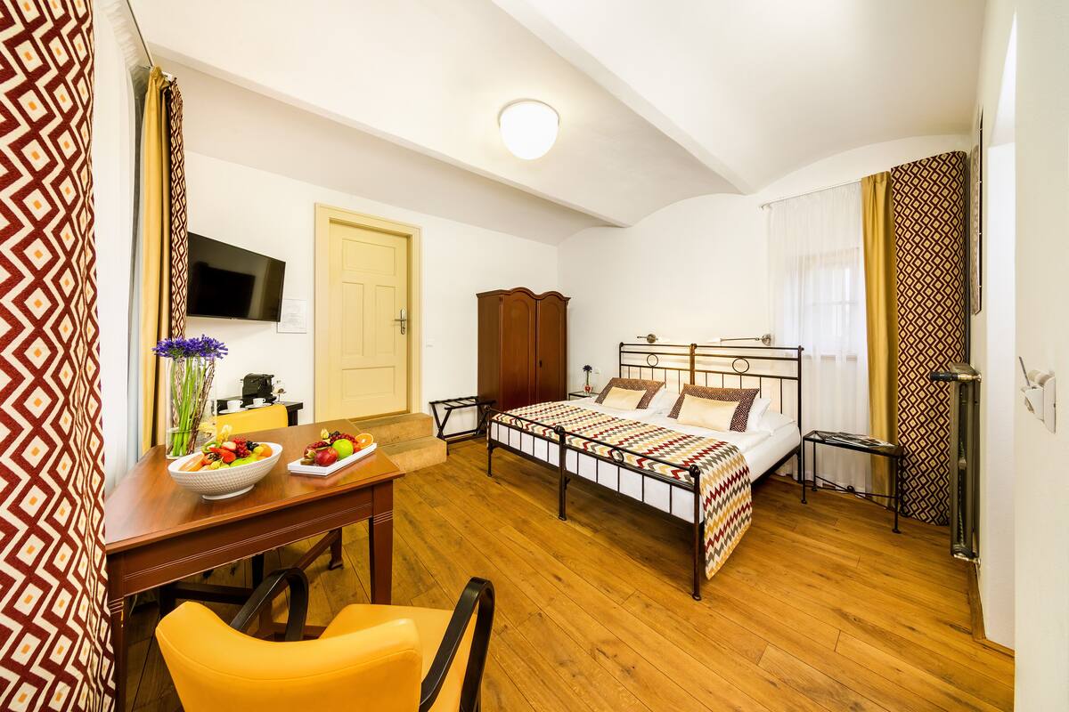 Un dormitorio con cama, mesita de noche y escritorio con silla.