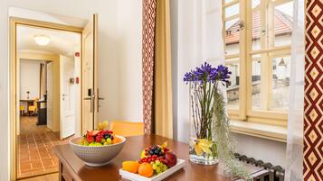 A dining table with a fruit bowl and a vase with flowers.