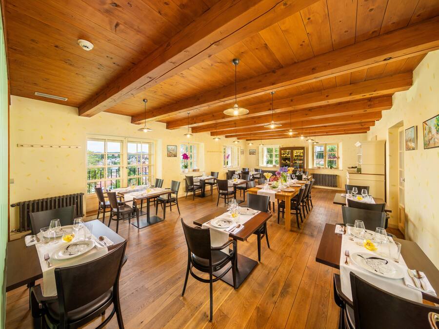 A restaurant with wooden ceilings and tables set for dining.