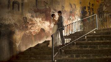 Una pareja parada en una escalera de piedra con un mural al fondo.