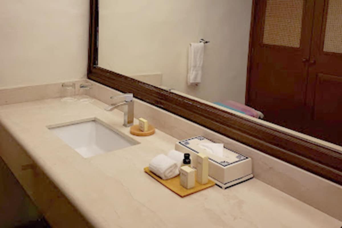 Un baño de hotel con un espejo grande, un lavabo y artículos de aseo en la encimera.