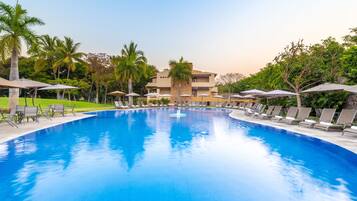 Relax by the pool surrounded by palm trees and lounge chairs.