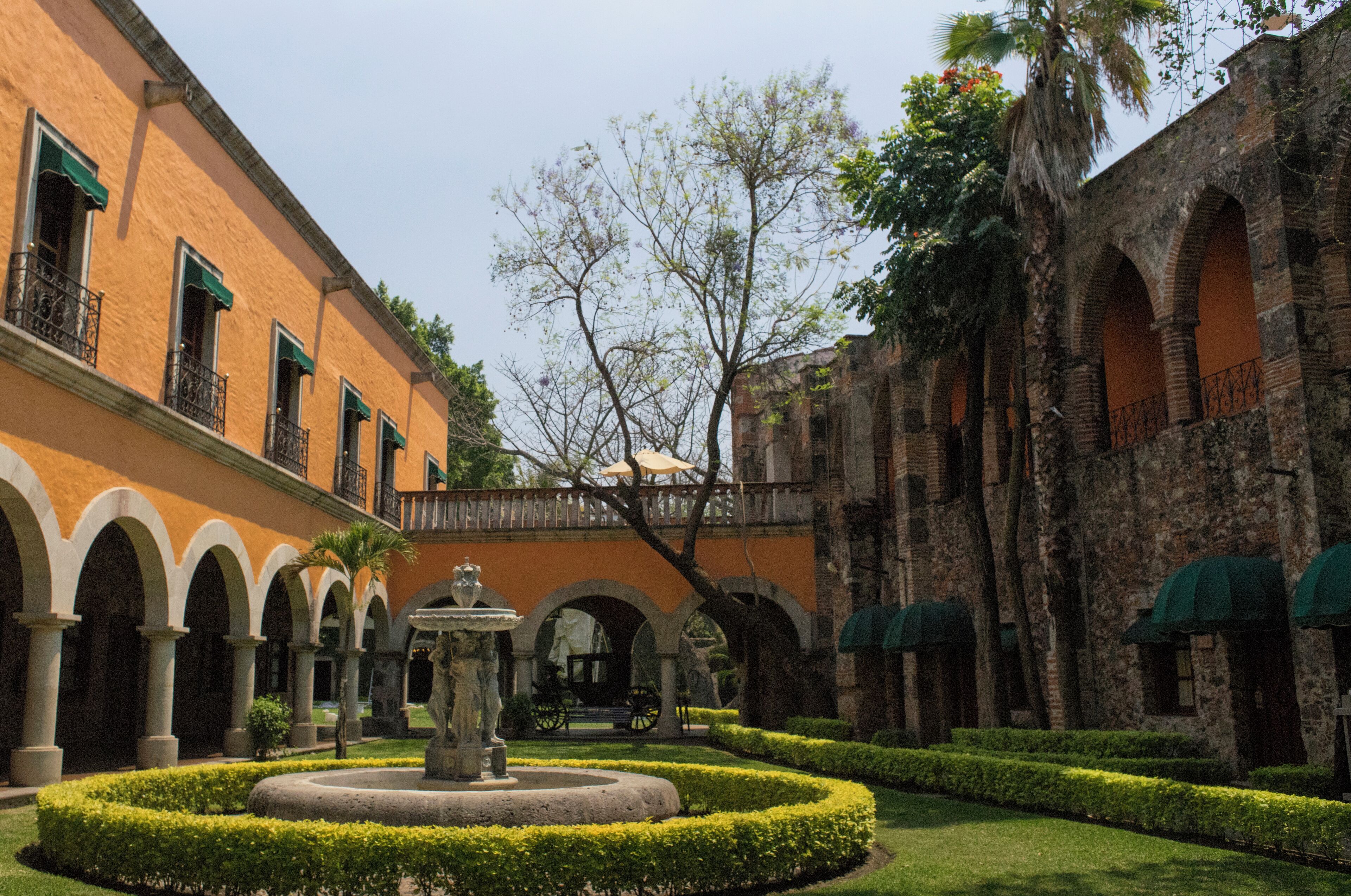 Un patio con una fuente, arcos y un puente.