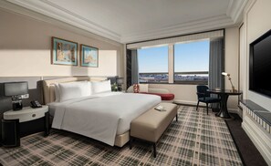 A hotel room with a large bed, a desk with a lamp, a TV, a sofa, and a view of the city. - Pullman Beijing South - Newly Renovated (Beijing)