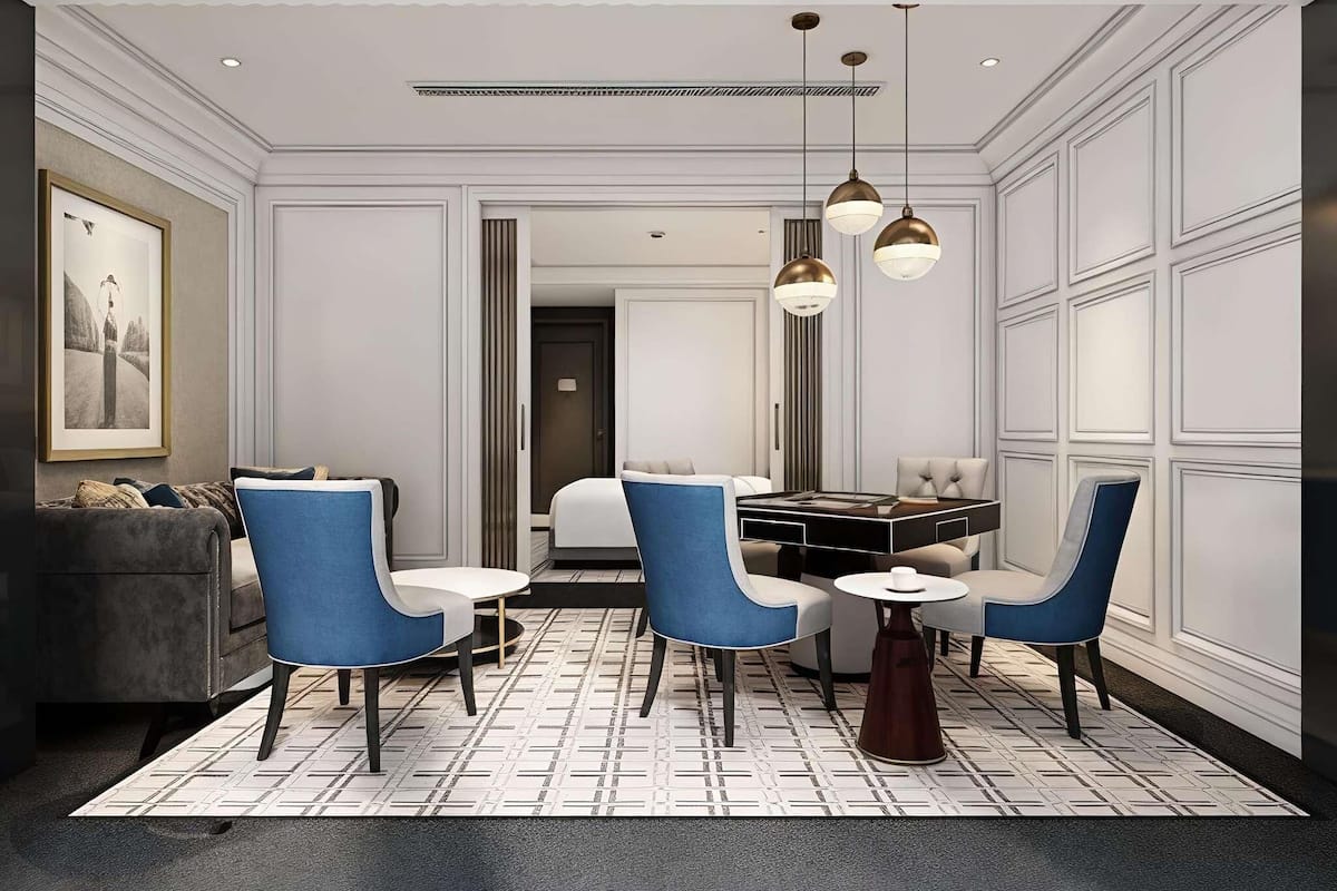 A modern hotel room with a dining area, a sofa, and a large window.