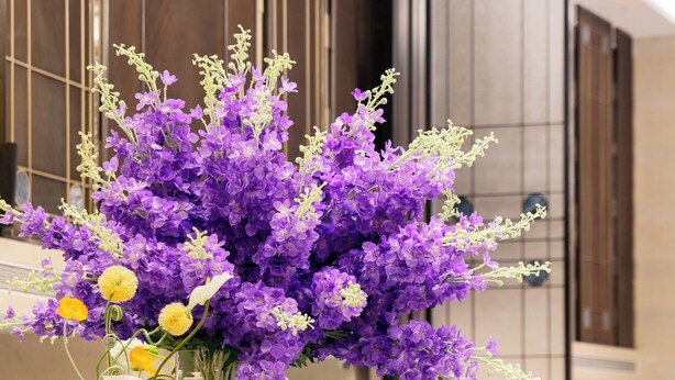 A hotel reception area with a marble counter, multiple flower arrangements, and a modern interior design. - Pullman Beijing South - Newly Renovated (Beijing)