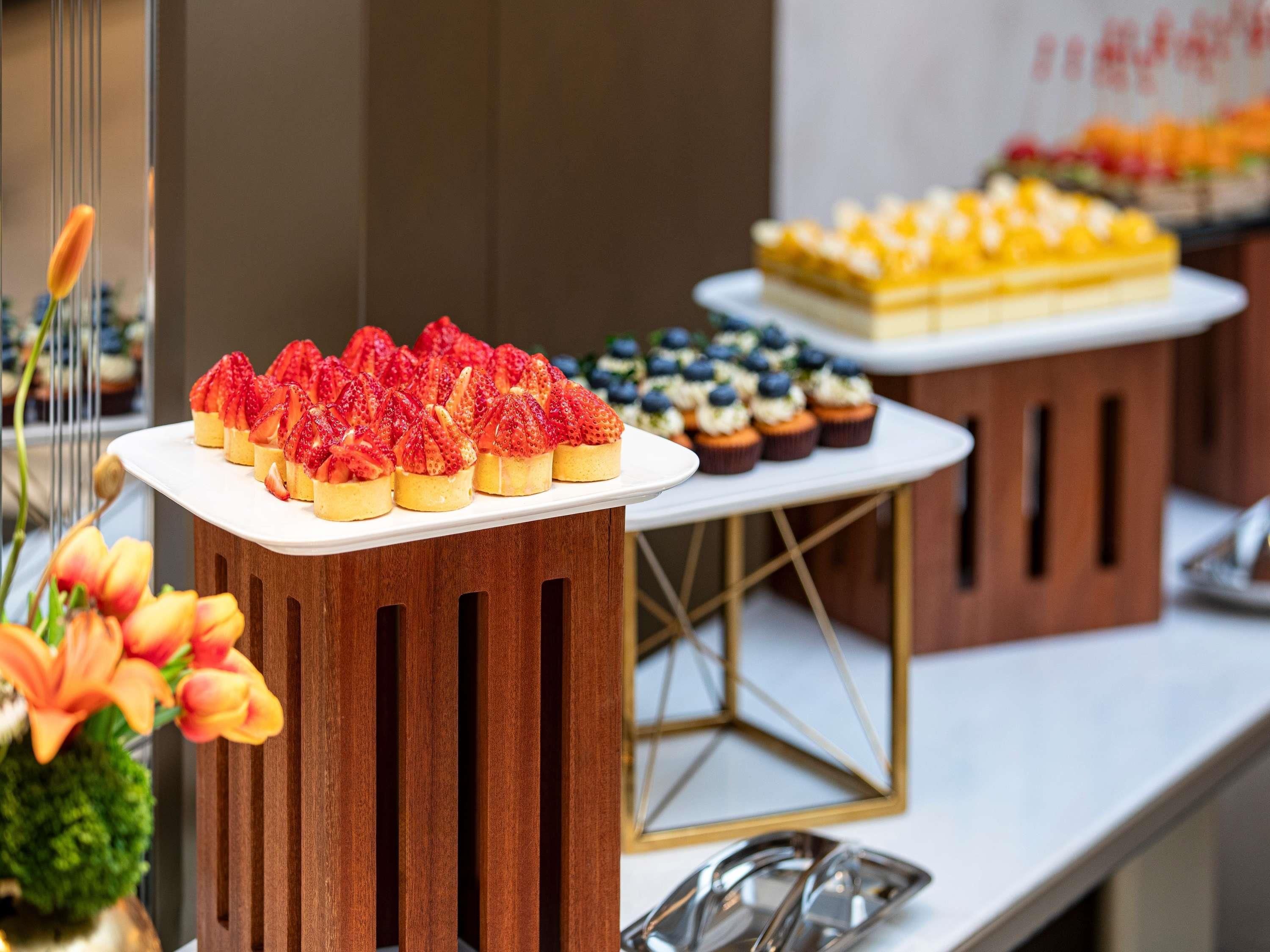 A buffet table with various desserts, including strawberry-topped pastries and blueberry-topped cupcakes.