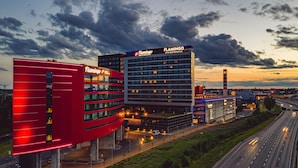 A modern hotel with a prominent red facade and multiple floors, located adjacent to a highway. - Break Sokos Hotel Flamingo (Vantaa)