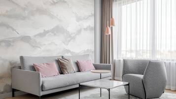 Una sala moderna con un sofá gris, una mesa de centro redonda y un sillón gris.