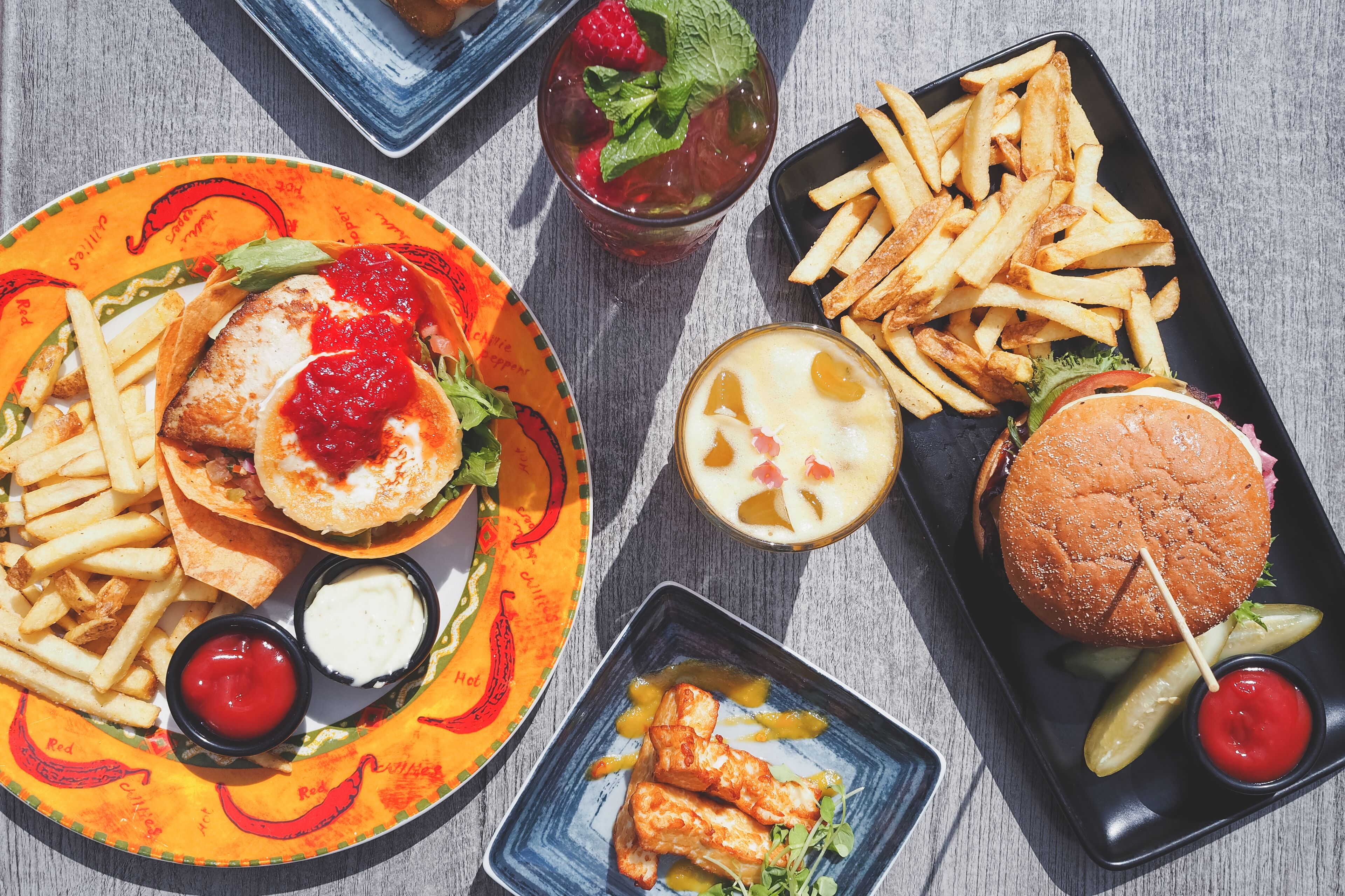 A variety of food items including a burger, fries, and a plate with a fish sandwich.