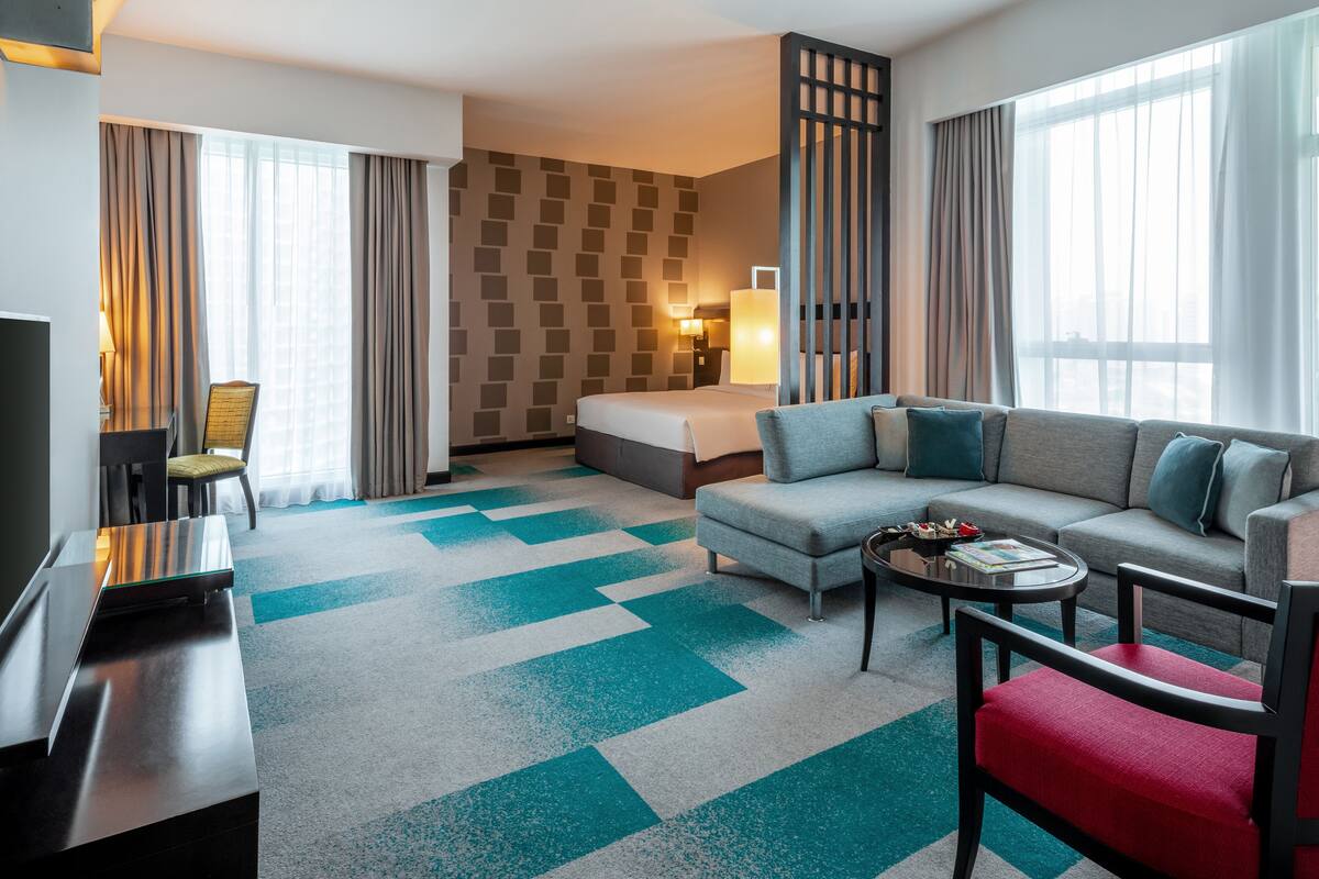 Een moderne hotelkamer met een groot bed, een bank, een salontafel en een televisie.