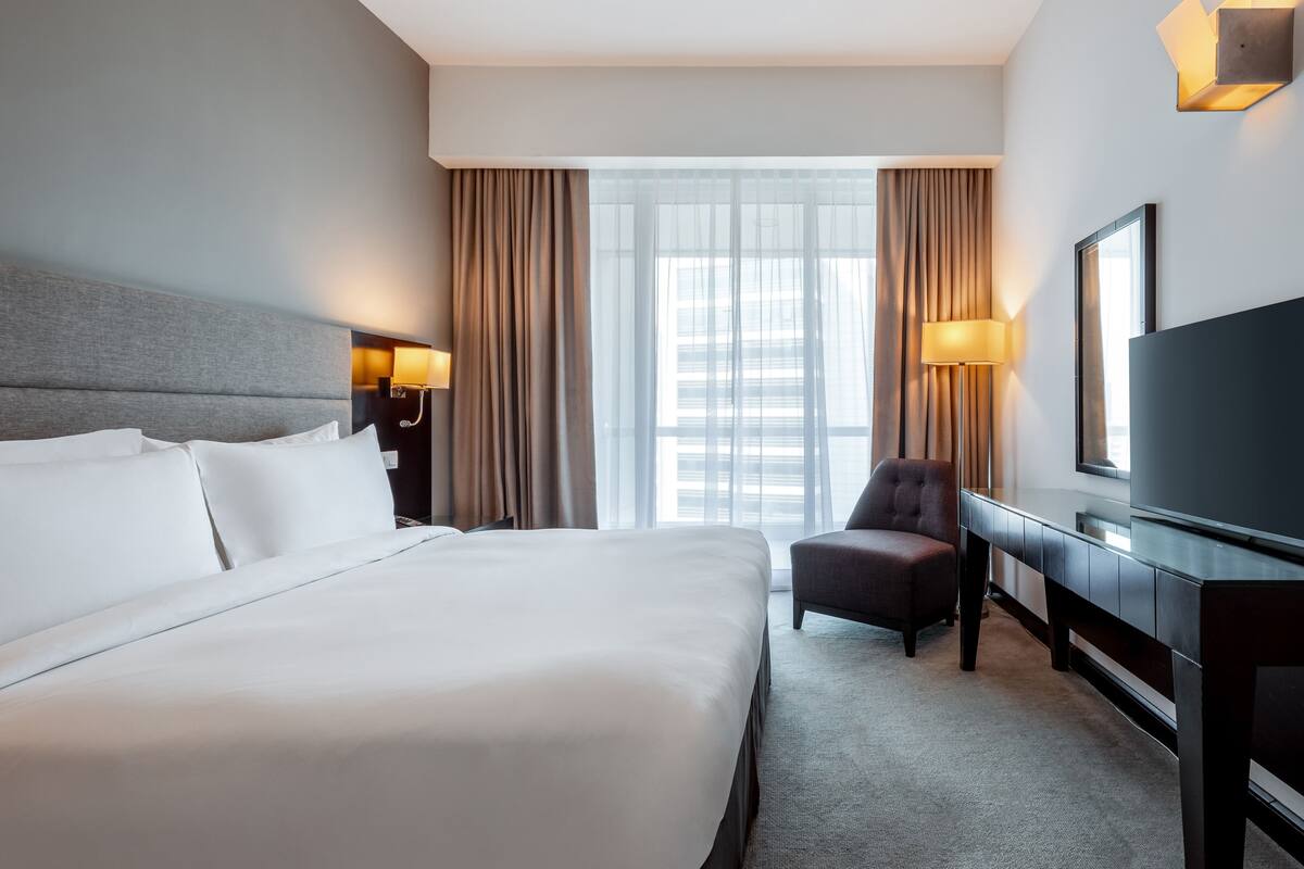 Een hotelkamer met een groot bed, een bureau met een flatscreen televisie en een stoel.