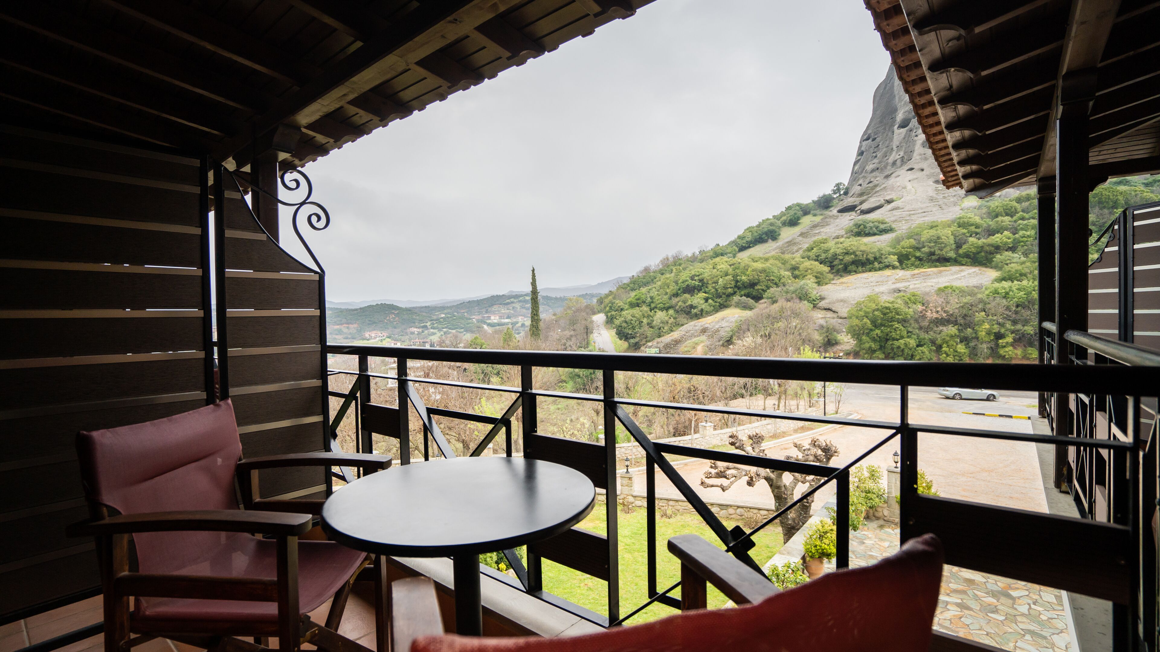 Un balcón con mesa y sillas, con vistas a un paisaje montañoso.