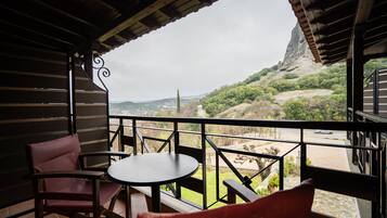 Un balcón con mesa y sillas, con vistas a un paisaje montañoso.