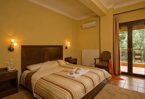 A hotel room with a large bed, a nightstand, a chair, and a view of the outdoors through a sliding glass door. - Dellas Boutique Hotel (Kalabaka)