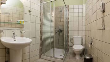 A bathroom with a glass-enclosed shower, a sink, a toilet, and a telephone.
