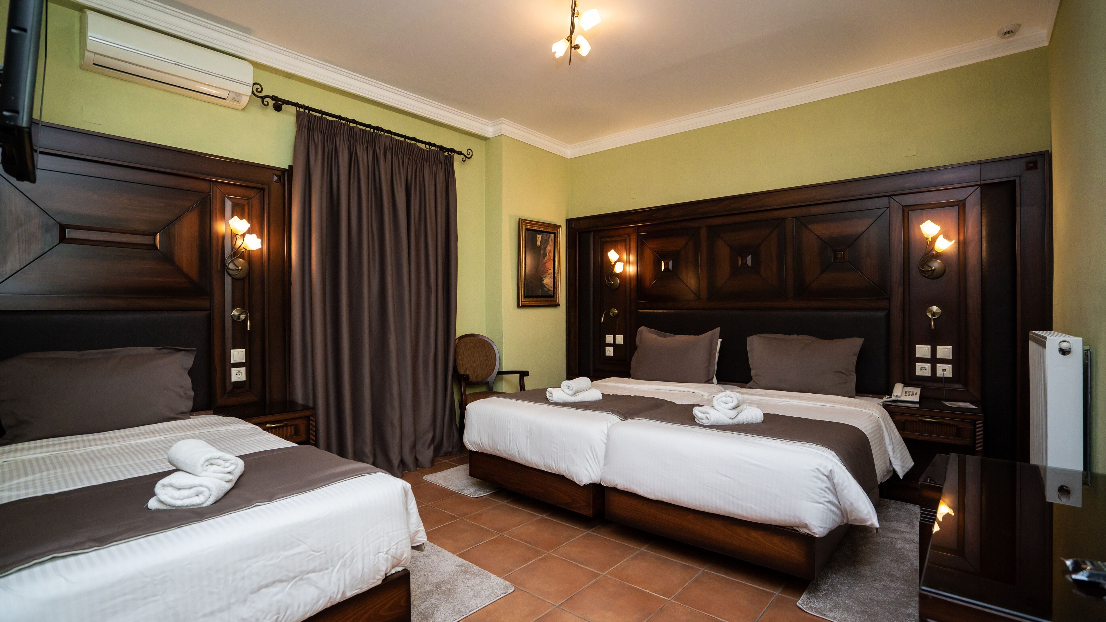 A hotel room with two beds, a large mirror, a wooden headboard, a painting, and a radiator.