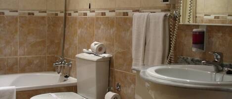 Une salle de bain équipée d’une baignoire, de toilettes, d’un bidet et d’un lavabo.
