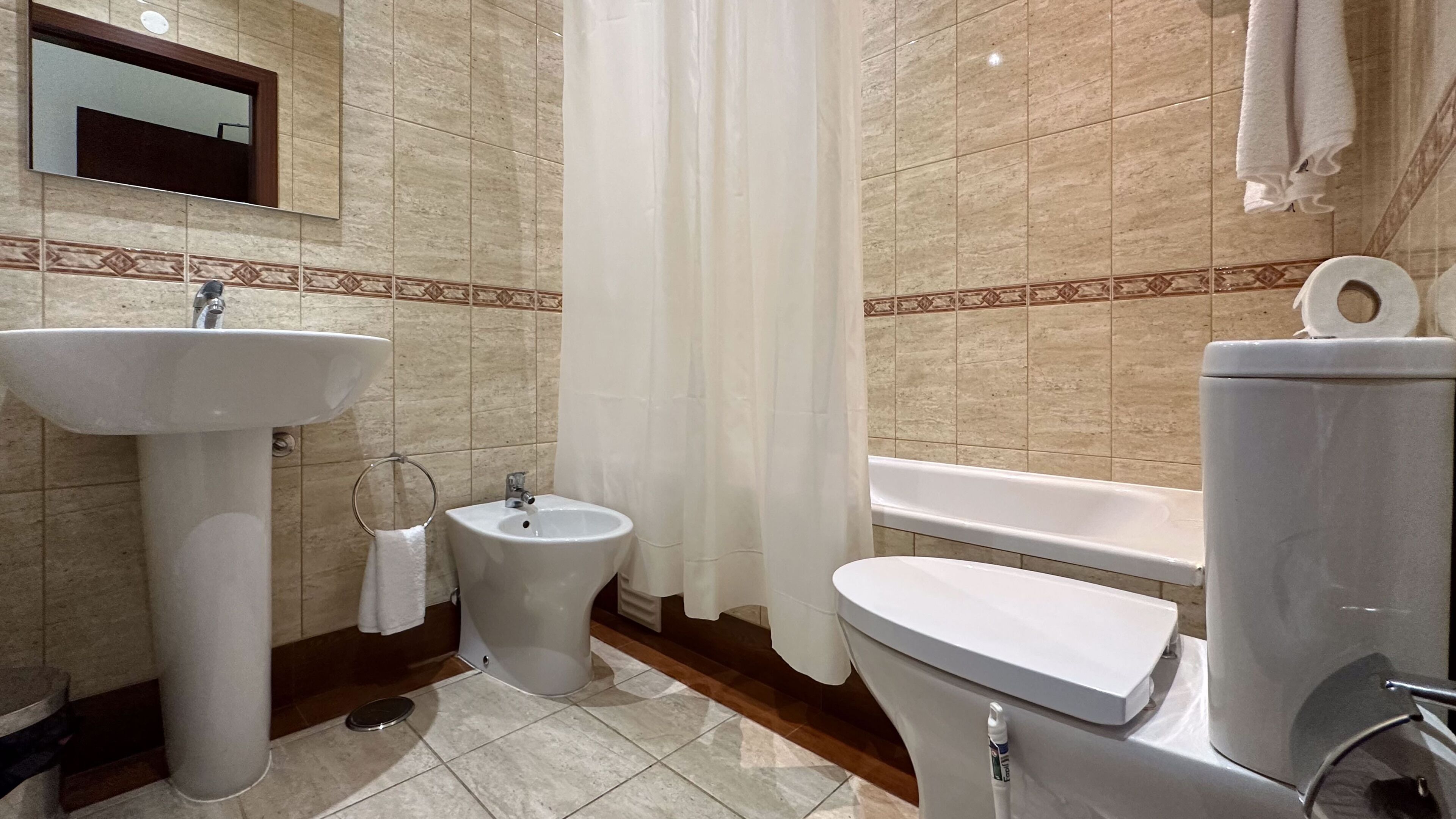A bathroom with a sink, bidet, toilet, and bathtub.