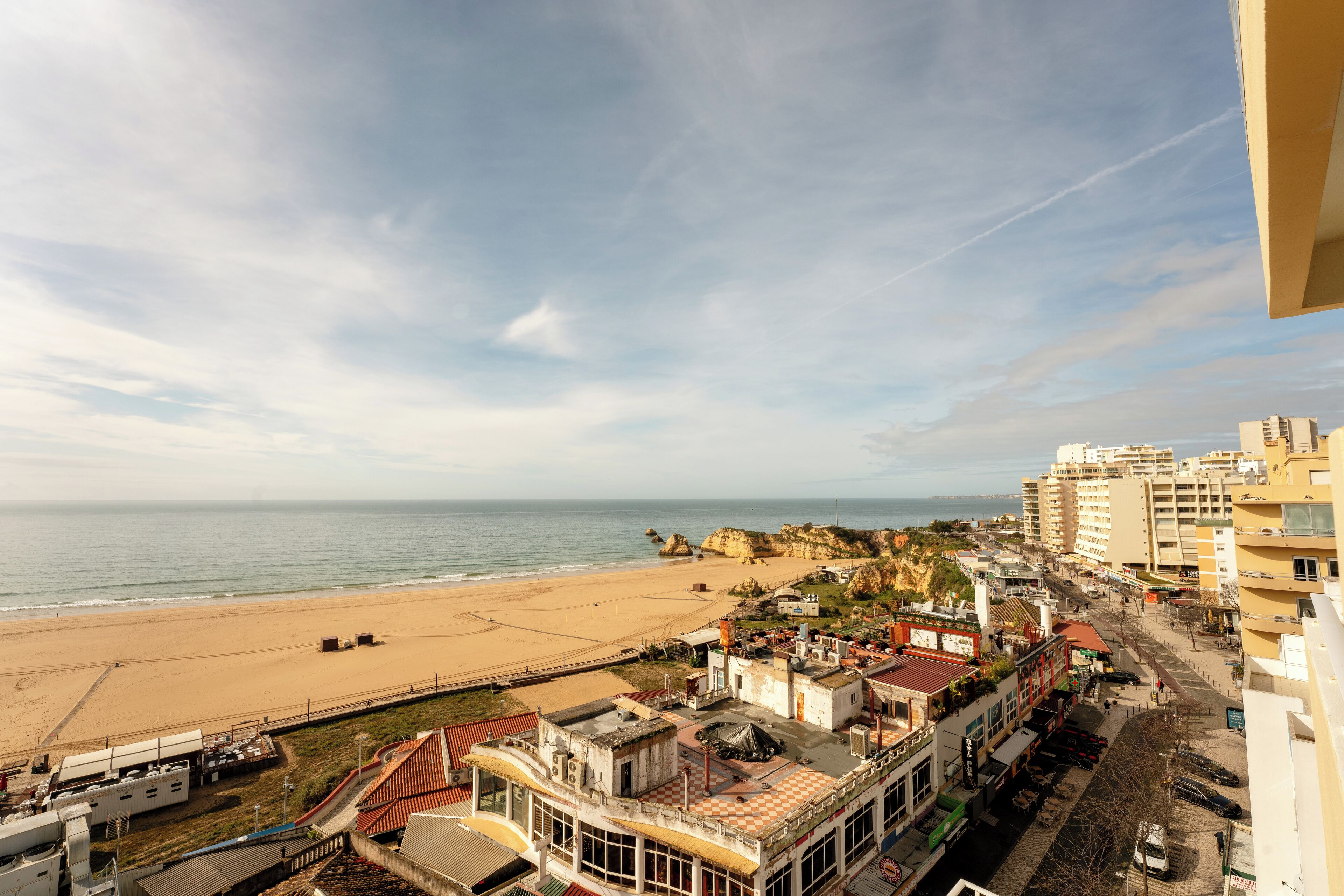 A coastal cityscape with a beach, buildings, and a clear sky.