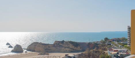 A coastal view with a beach, cliffs, and a building with a balcony.