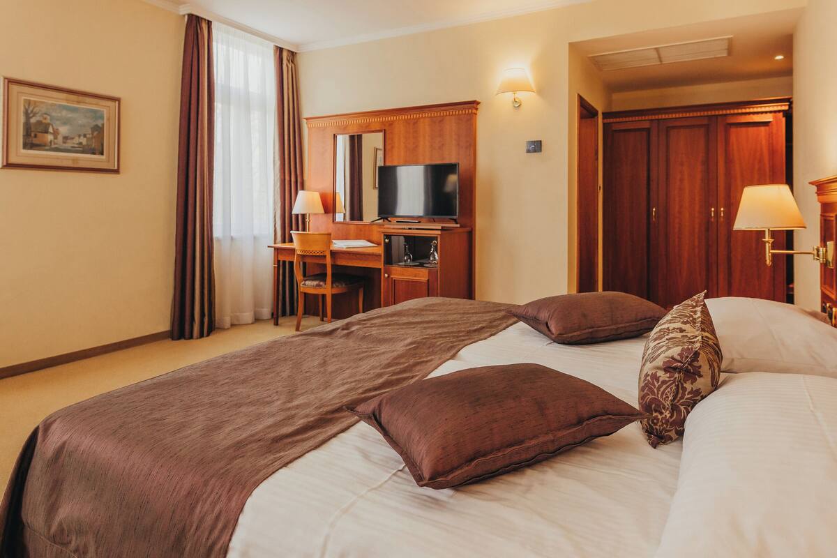 Een hotelkamer met een groot bed, een bureau met stoel, een televisie en een kledingkast.
