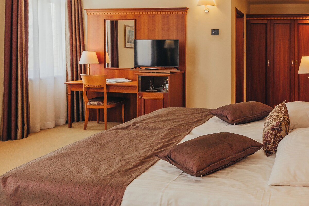 Ein Hotelzimmer mit Bett, Schreibtisch, Fernseher und Lampe.