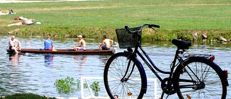 A bicycle with a basket parked by a calm body of water.