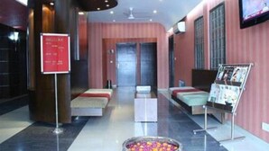 A hotel lobby with a reception desk, seating area, and a TV screen. - Hotel Grand Peepal (New Delhi)