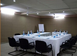 A conference room with a long table, black chairs, water bottles, and a whiteboard. - Hotel Grand Peepal (New Delhi)