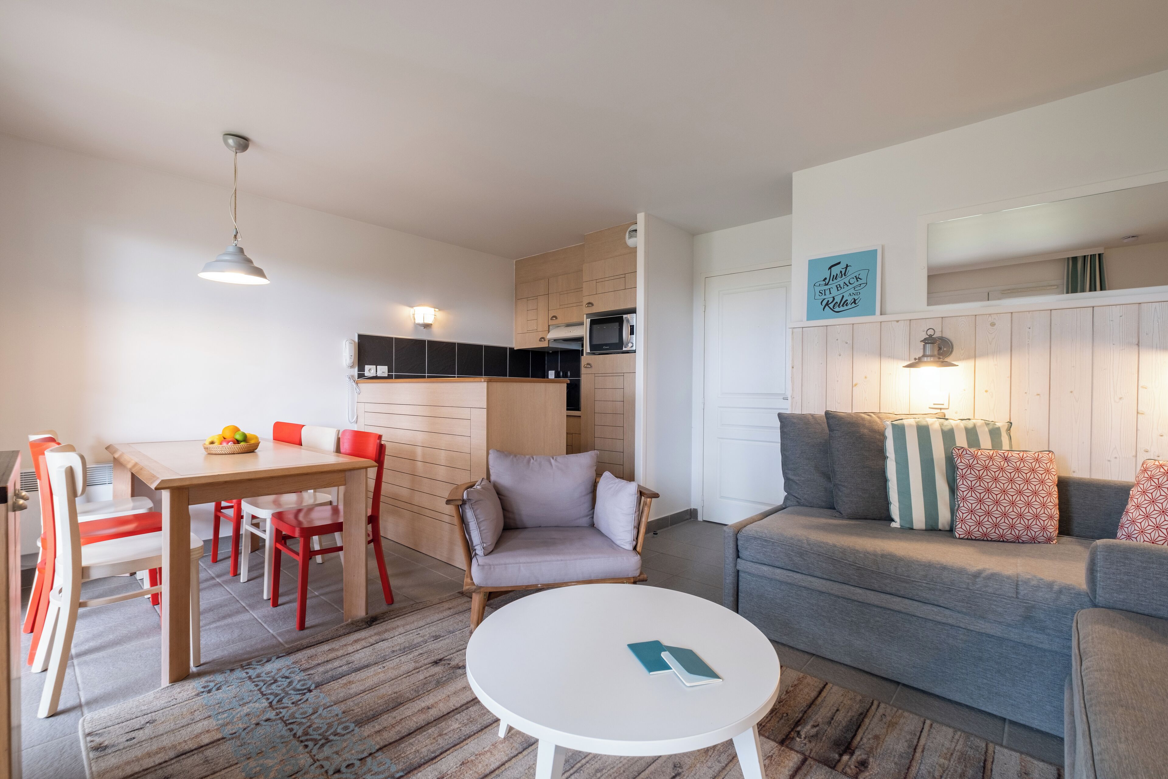 A compact living space with a dining area, a sofa, a small table, and a kitchen area.