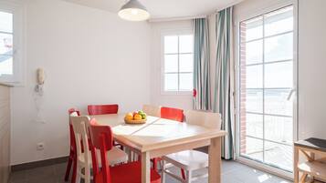 A dining area with a table, chairs, and a fruit bowl.