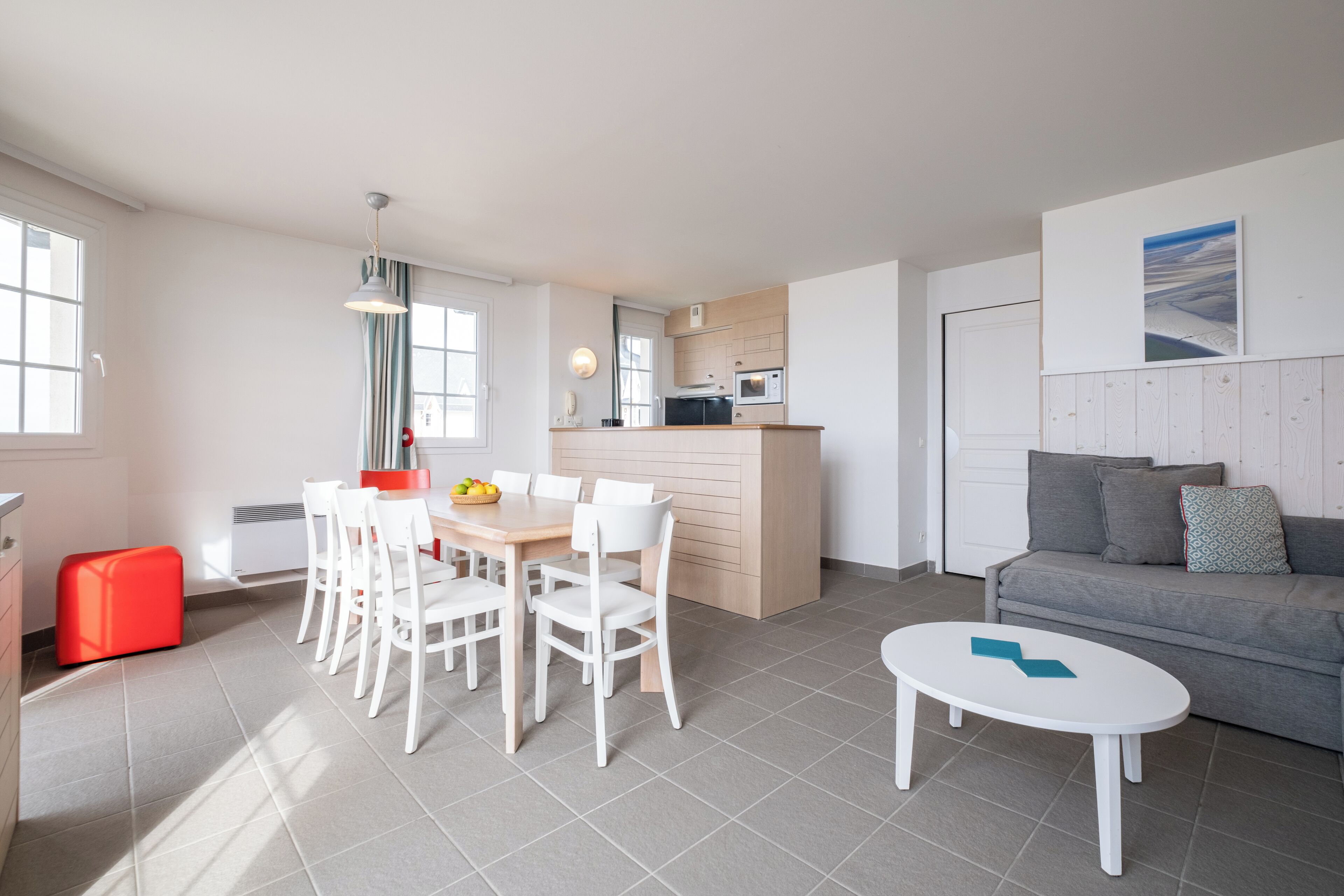 Una sala moderna con comedor, una cocina y un sofá gris.