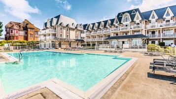 A hotel with a swimming pool, multiple balconies, and a traditional architectural style.