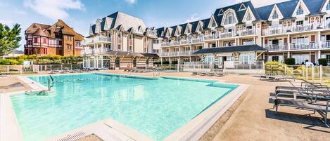 Ein Hotel mit Schwimmbad, mehreren Balkonen und traditioneller Architektur.