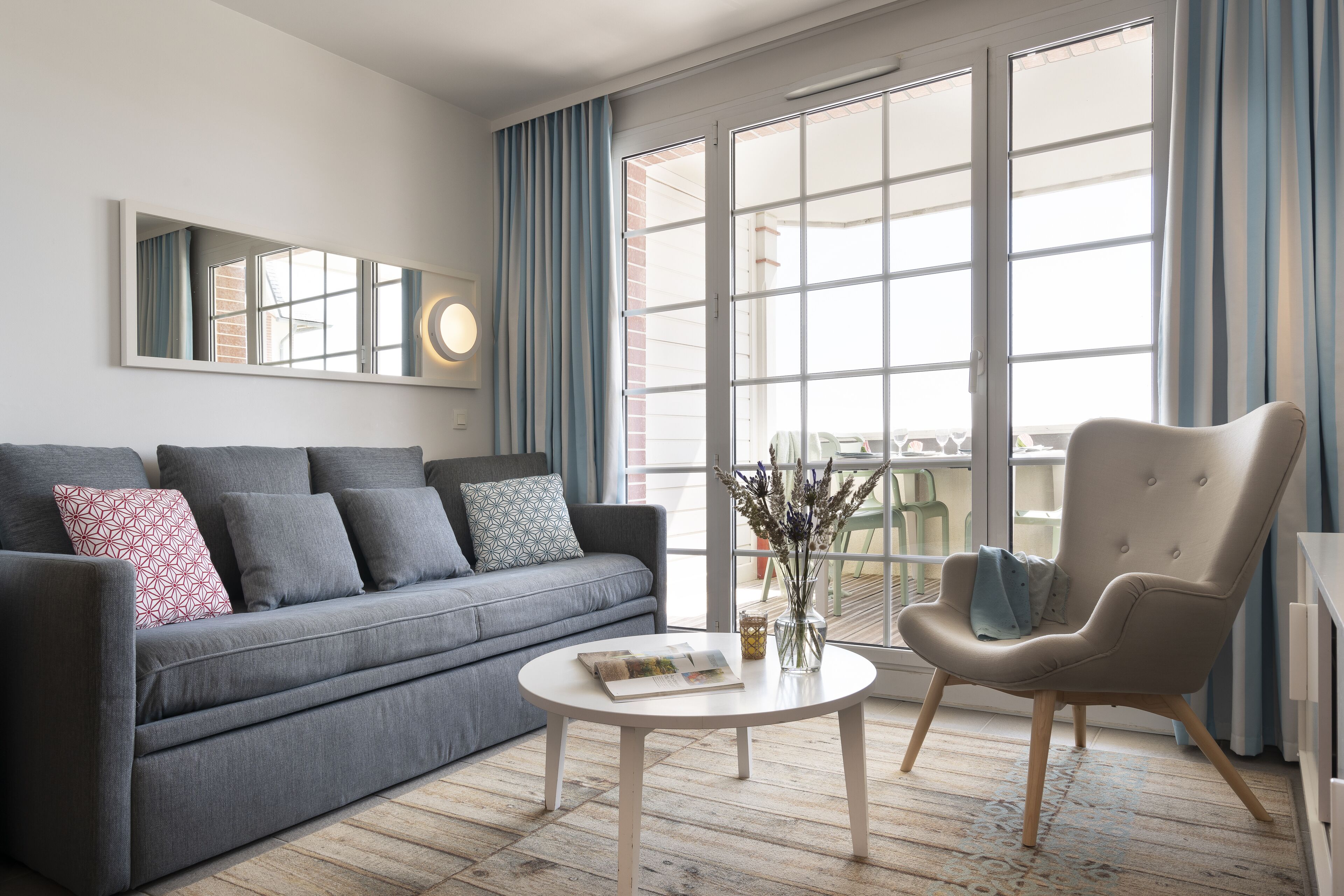 A modern living room with a grey sofa, a round coffee table, and a beige armchair.