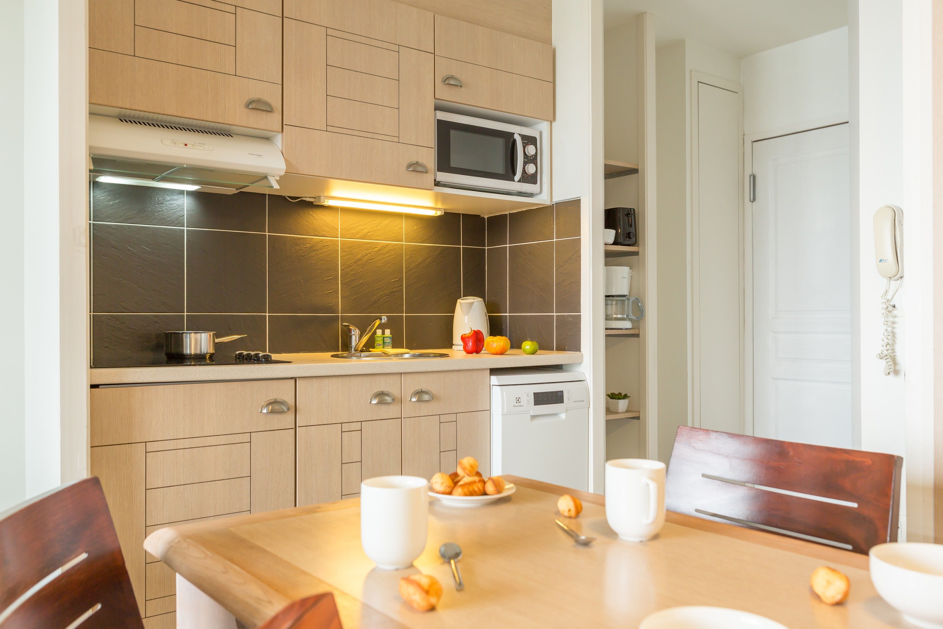Una cocina moderna con armarios de madera, un microondas y una mesa de comedor con sillas.