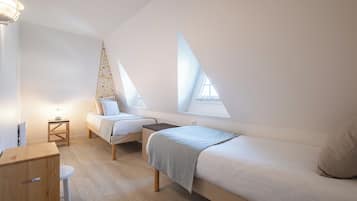 Un dormitorio pequeño y moderno con dos camas, un aparador de madera y una mesita.
