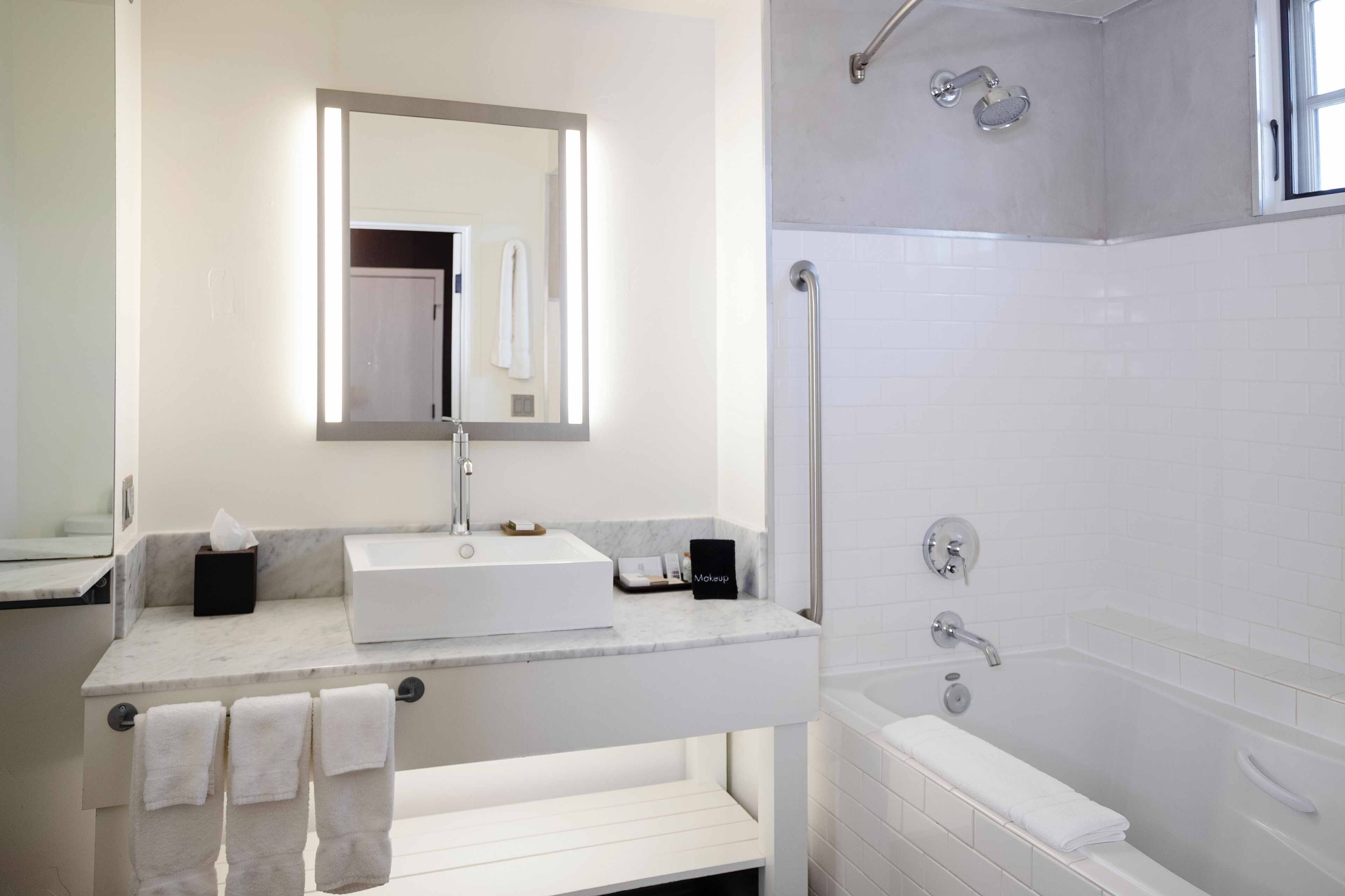 Une salle de bain moderne avec un lavabo blanc, un miroir et une baignoire.