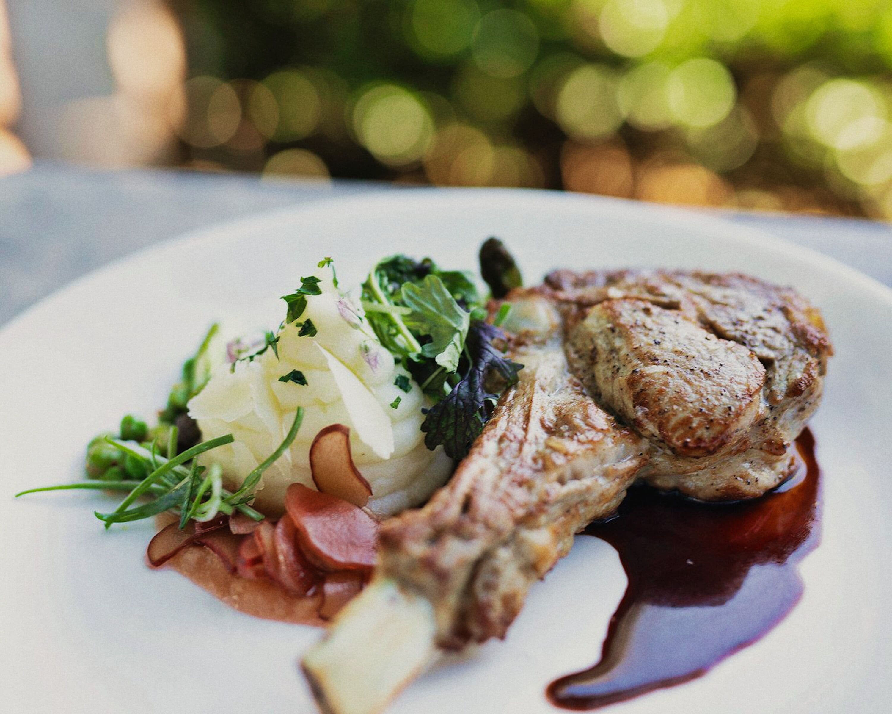 A plate with a grilled meat, vegetables, and a sauce.