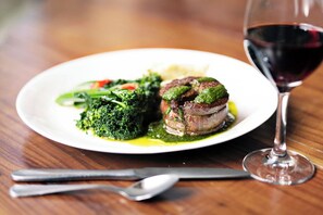 A plate of food with a glass of red wine on a wooden table.