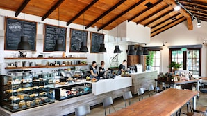 A cafe with a wooden ceiling, menu boards, a counter with staff, and a display case with food items.