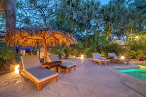 An outdoor pool area with lounge chairs and a thatched umbrella. - Hotel Pasatiempo (Tamarindo)