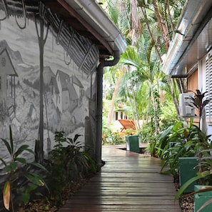 A wooden pathway leading to a building with a mural of houses and mountains.