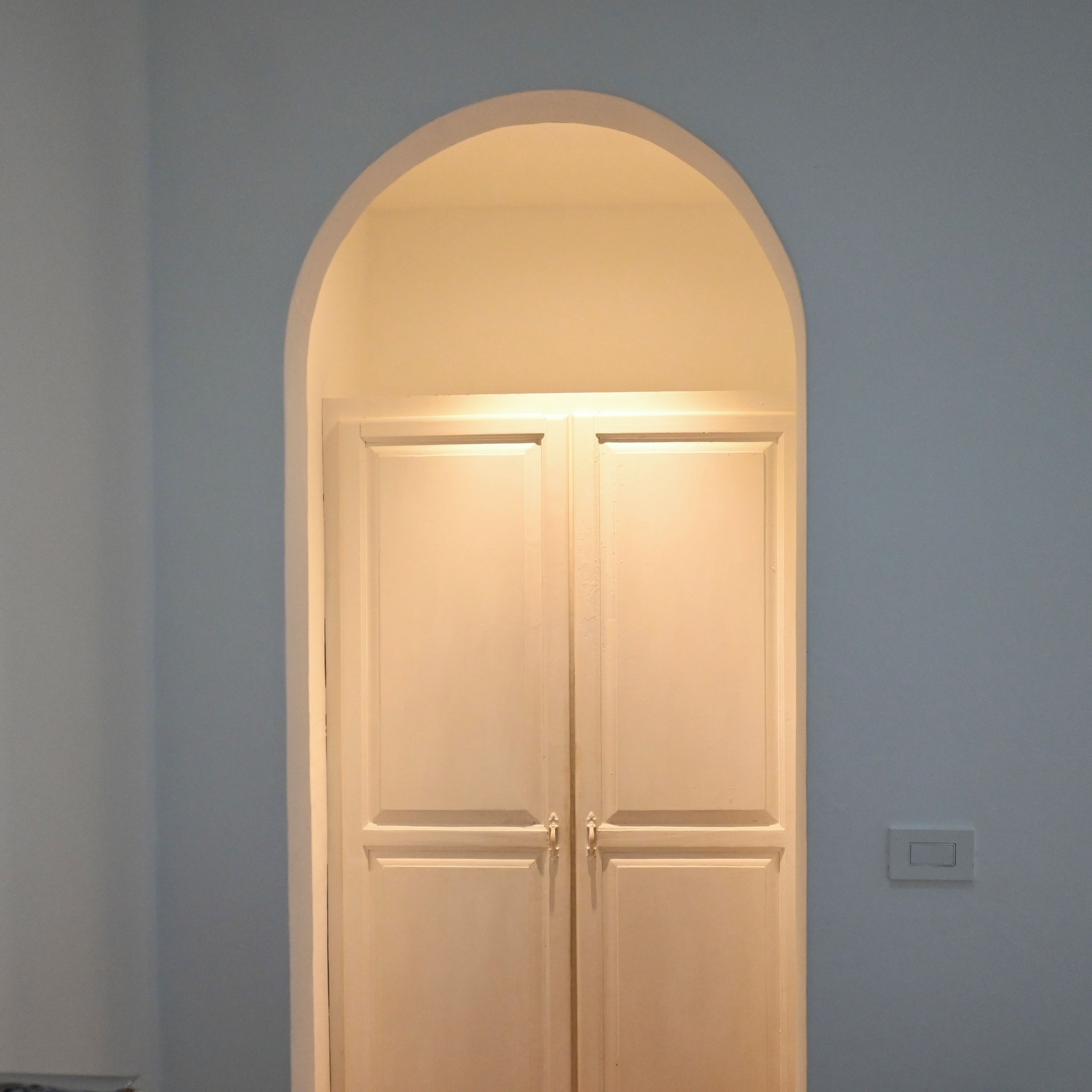 Puerta doble cerrada con marco blanco y una luz pequeña en la parte superior.